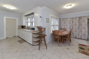 Cocina compacta con armarios blancos, microondas y comedor con mesa y sillas de madera.