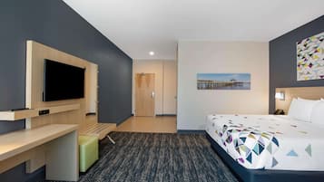 Quarto de hotel moderno com uma cama grande, uma escrivaninha, televisão de tela plana e uma pintura de um cais.