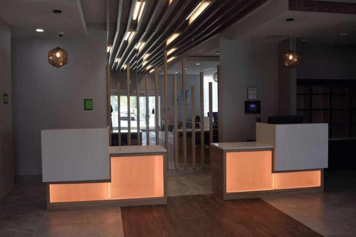 Un'area reception dal design moderno, con scrivania, divisorio in vetro e soffitto con illuminazione lineare.
