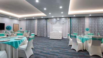 A banquet hall with round tables, white chairs, and teal accents.