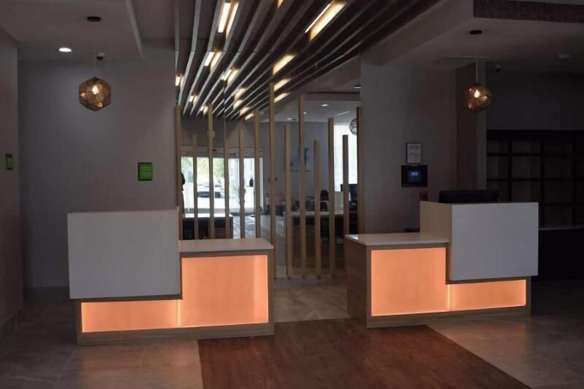 Een receptiegedeelte met een modern design, met een receptiebalie, een glazen scheiding en een plafond met lineaire verlichting.