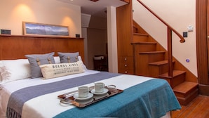 A hotel room with a bed, a tray with cups and saucers, a wooden staircase, and a painting on the wall. - Avenida Tango (Buenos Aires)