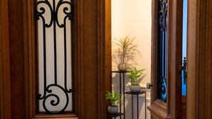 A wooden door with a black metal design, leading to a room with a potted plant and a small table. - Avenida Tango (Buenos Aires)