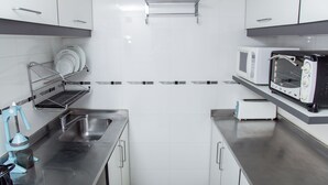 A modern kitchen with stainless steel countertops, a microwave, a toaster, and a dish rack. - Avenida Tango (Buenos Aires)