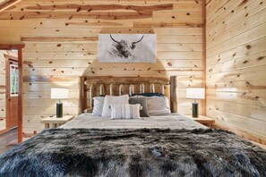 A log cabin bedroom with a bed, two bedside lamps, and a wall-mounted artwork of a bull's head. - 6-Bedroom All-Ensuite Cabin with Indoor Pool & Theater Near Dollywood (Pigeon Forge)
