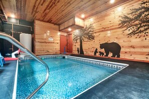 A swimming pool with a wooden interior, a basketball hoop, and a bear mural on the wall. - 6BR Cabin, All Ensuite | Indoor Pool + Theater (Pigeon Forge)