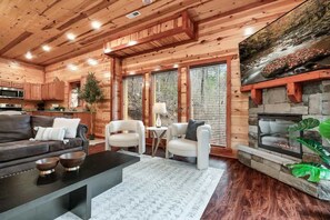 A wooden interior with a fireplace, seating area, and kitchen. - 6-Bedroom All-Ensuite Cabin with Indoor Pool & Theater Near Dollywood (Pigeon Forge)