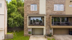 A two-story residential building with a garage, a balcony on the upper floor, and a small front yard. - The Abshier - Near U of A - Quiet Getaway (Fayetteville)