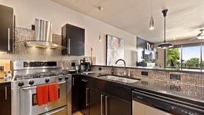A modern kitchen with stainless steel appliances, black cabinetry, and a tiled backsplash. - The Abshier - Near U of A - Quiet Getaway (Fayetteville)