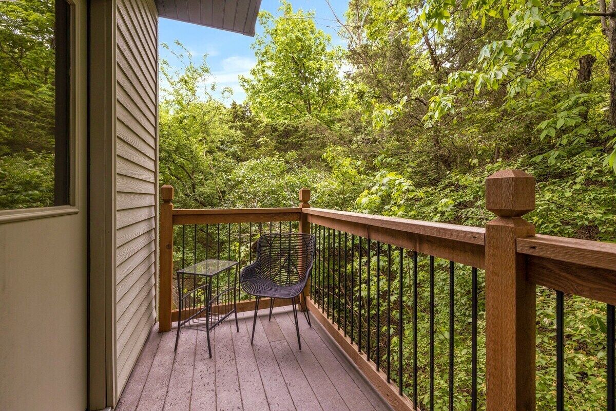 A wooden deck with a railing, a table, and two chairs.