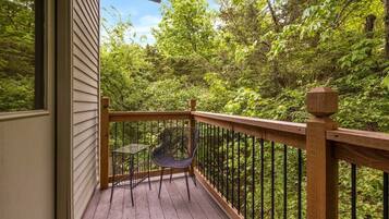 A wooden deck with a railing, a table, and two chairs.