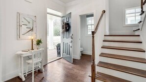 A staircase leading to a second floor with a wooden handrail and a white wall with a clock. - The SoFay Farmhouse - 1 mi From U of A (Fayetteville)