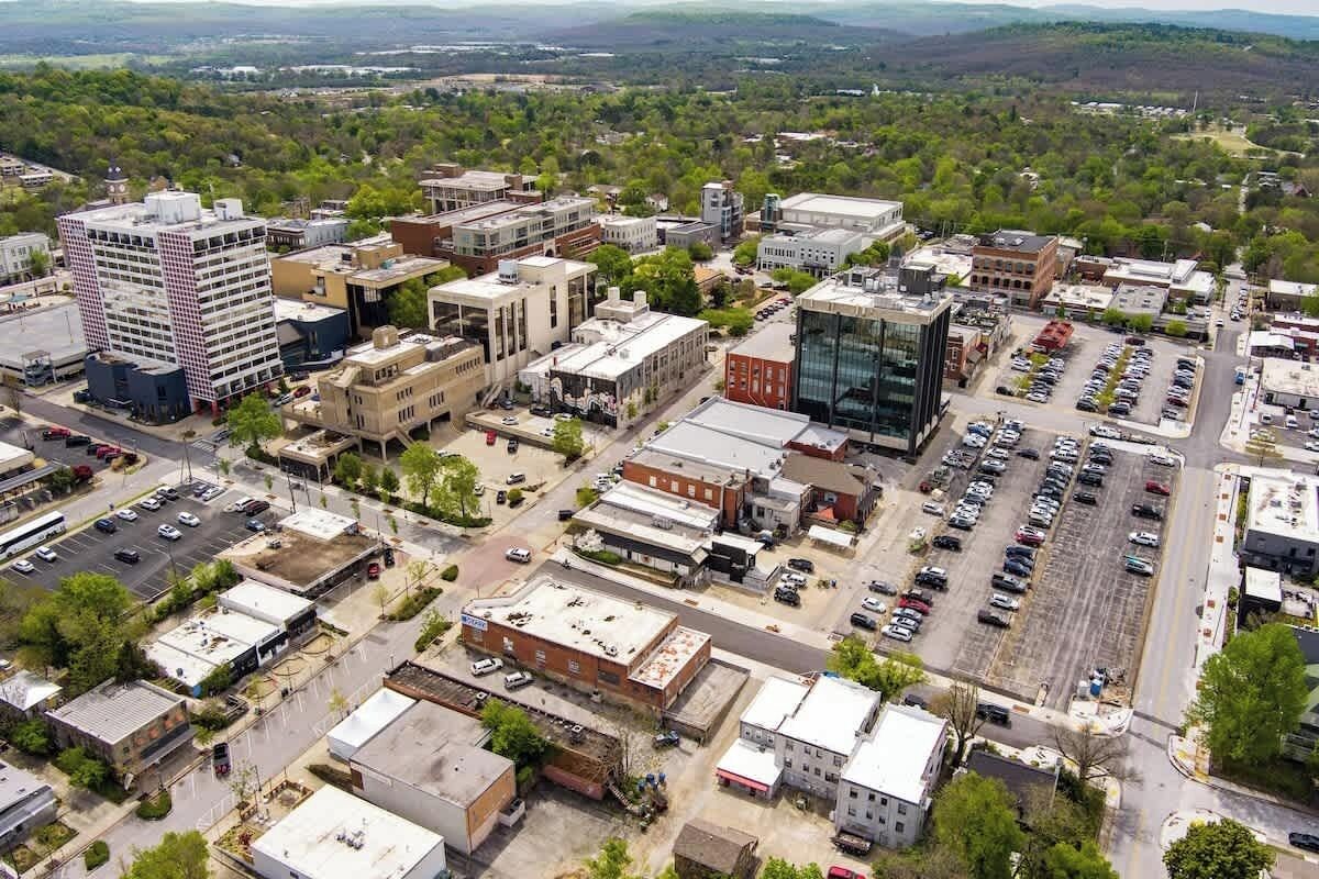 An aerial view of a downtown area with various buildings, parking lots, and streets.