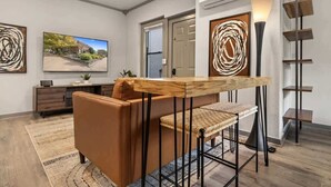Ein modernes Wohnzimmer mit einer Couch, einem Couchtisch und einem Fernseher. Eine Tür führt in einen anderen Raum, und eine Treppe ist ebenfalls vorhanden.