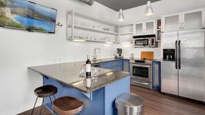 A modern kitchen with a central island, stainless steel appliances, and blue cabinetry. - The East View - Downtown - Steps to Dickson (Fayetteville)