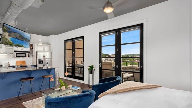 A modern apartment with a kitchen, dining area, and a balcony with a city view. - The East View - Downtown - Steps to Dickson (Fayetteville)