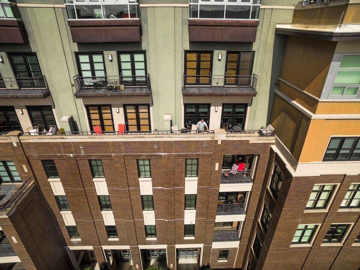 A multi-story building with a brick facade, multiple balconies, and large windows.