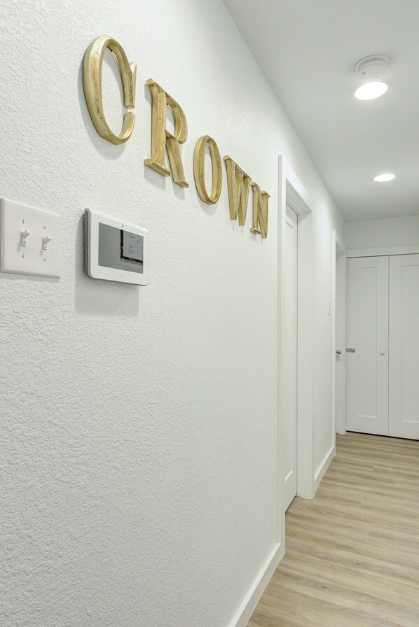 A hallway with a white textured wall, a thermostat, and a door.