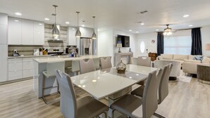 A modern kitchen with white cabinets, a central island, and pendant lighting. - Crown - A Birdy Vacation Rental (San Antonio)