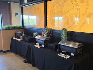 A buffet setup with various food stations labeled, including eggs, sausage, and bacon.
