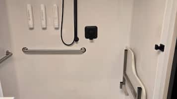A white shower stall with a handheld showerhead, a handheld shower attachment, and a grab bar.