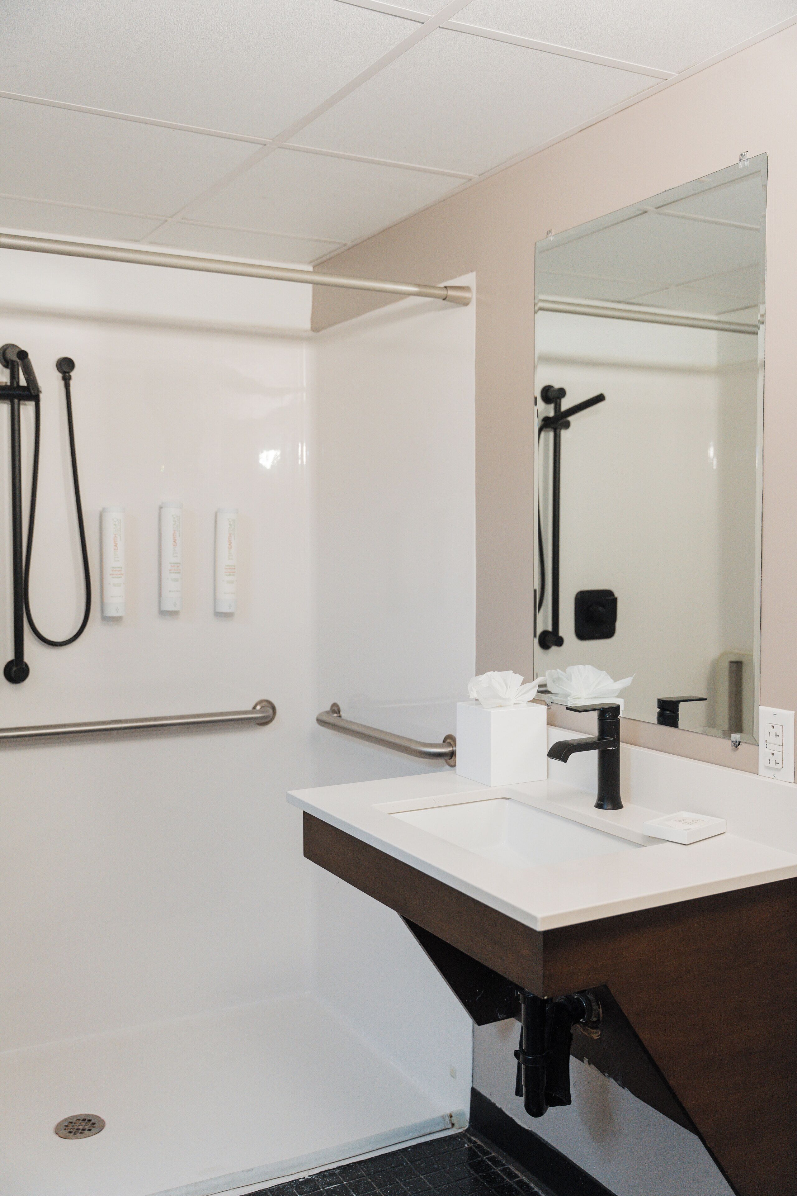 A modern bathroom with a white sink, a large mirror, and a walk-in shower.
