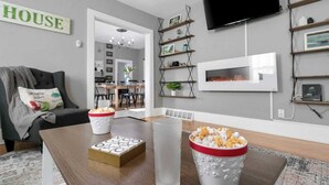 A modern living room with a flat-screen TV, a coffee table with snacks, and a cozy seating area.