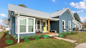 A single-story house with a front porch, large windows, and a well-maintained lawn.
