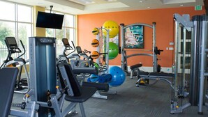Un gimnasio con máquinas de cardio, equipo de levantamiento de pesas y pelotas de ejercicio.