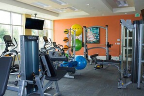 Une salle de sport équipée de machines de cardio, de matériel de musculation et de ballons d’exercice.