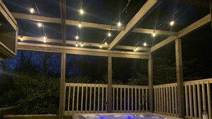A hot tub with a wooden deck and string lights.