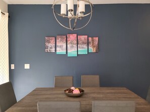 Uma sala de jantar com uma mesa de madeira, quatro cadeiras e um lustre.
