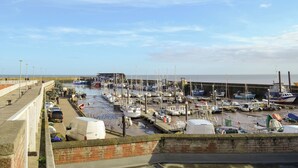 Un port de plaisance avec des bateaux amarrés, une promenade piétonne et une vue sur la mer.