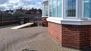 Un bâtiment en briques doté de grandes fenêtres et d’une rampe menant à une porte.