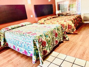A hotel room with two beds, each with floral bedding, wooden flooring, and a window with a view. - Embassy motel (Dallas)