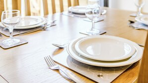 Ein Esszimmertisch ist mit Tellern, Besteck und Weingläsern gedeckt, was auf eine festliche Mahlzeit hindeutet.