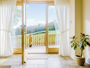 Ein Zimmer mit Blick auf ein hölzernes Tor, das zu einer Rasenfläche führt, sowie ein Blumentopf und ein Fliesenboden.