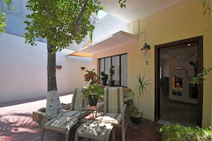 A sunlit patio with two chairs, a table, and potted plants.