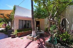 A courtyard with a palm tree, potted plants, and outdoor seating.