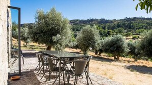 Un espace extérieur aménagé pour les repas, avec un sol en pierre, des chaises en métal et une table.