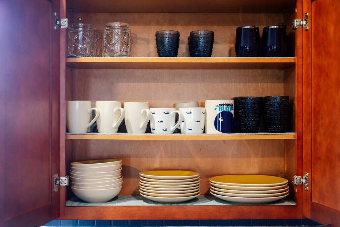 Un armario de madera con estantes que contienen diversos utensilios de cocina.
