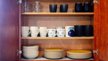 Un armario de madera con estantes que contienen diversos utensilios de cocina.