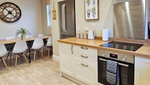 A modern kitchen with a stainless steel range hood, a built-in oven, and a wooden countertop.