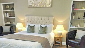 A neatly arranged bedroom with a large bed, two bedside tables with lamps, a bookshelf, and a decorative wall piece.