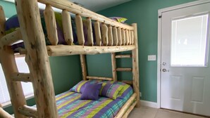 Un lit superposé avec une échelle en bois, une couverture à carreaux et une porte avec une fenêtre.
