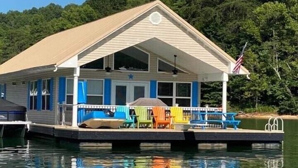 Une petite cabane à un seul étage, dotée d’un porche couvert et d’un drapeau, située sur un quai au-dessus de l’eau.