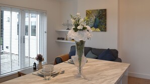 A dining area with a marble table, white plates, and clear glasses. There is a vase with white flowers on the table. - 1 bedroom accommodation in Hawley (Hawley)