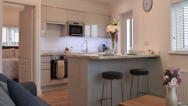 A modern kitchen with a central island, stainless steel appliances, and a dining area with bar stools. - 1 bedroom accommodation in Hawley (Hawley)
