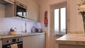 A modern kitchen with white cabinets, a stainless steel oven, a microwave, a toaster, and a fire extinguisher. - 1 bedroom accommodation in Hawley (Hawley)