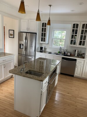 A modern kitchen with white cabinetry, stainless steel appliances, and a granite countertop.
